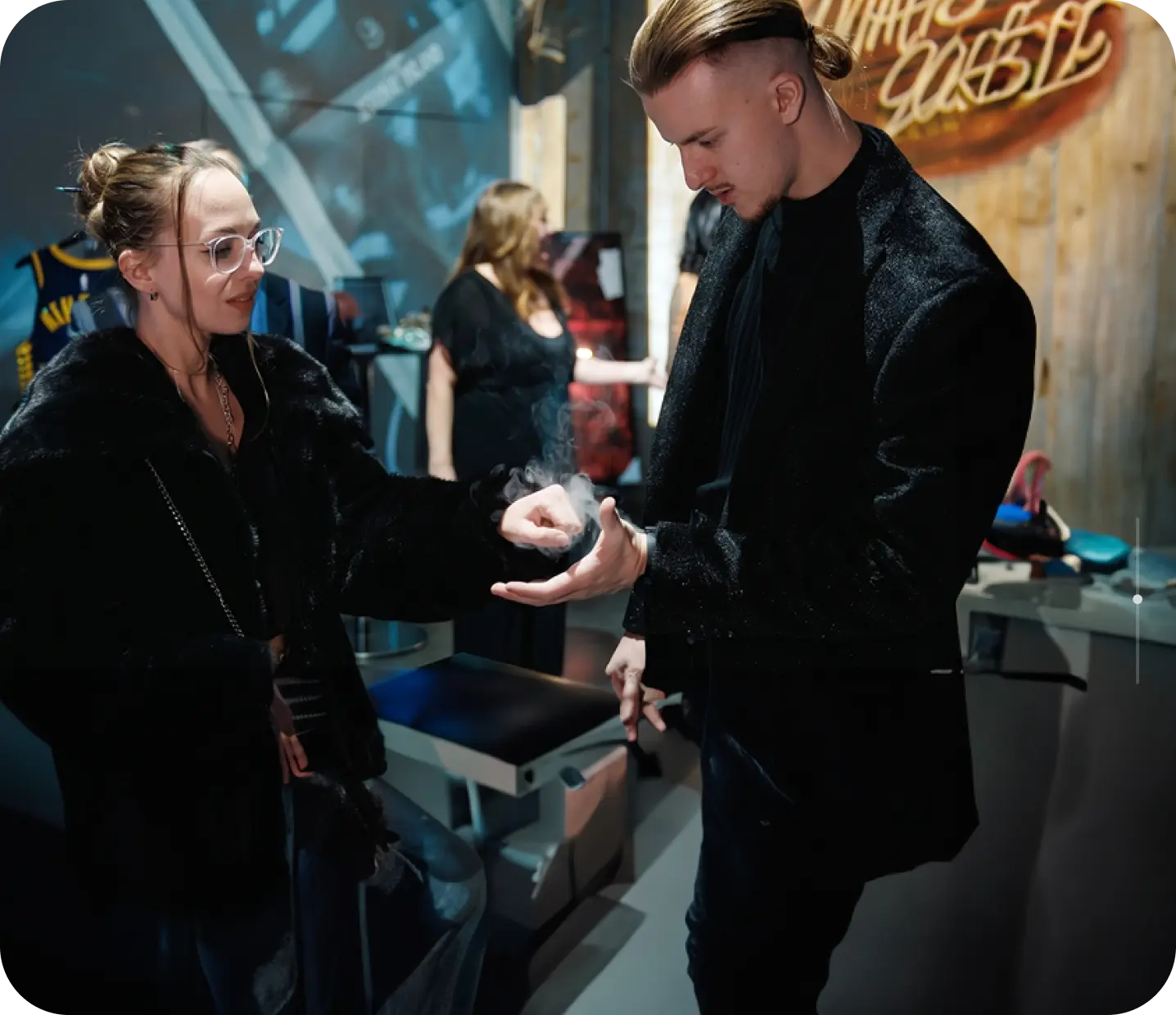 Roman performing close-up magic for a guest in glasses