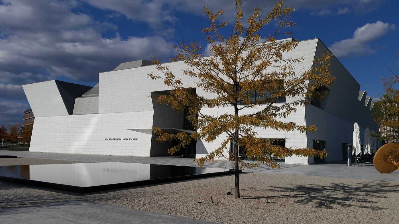 Aga Khan Museum in Toronto: white granite building behind a reflecting pool, with an autumn tree in the foreground