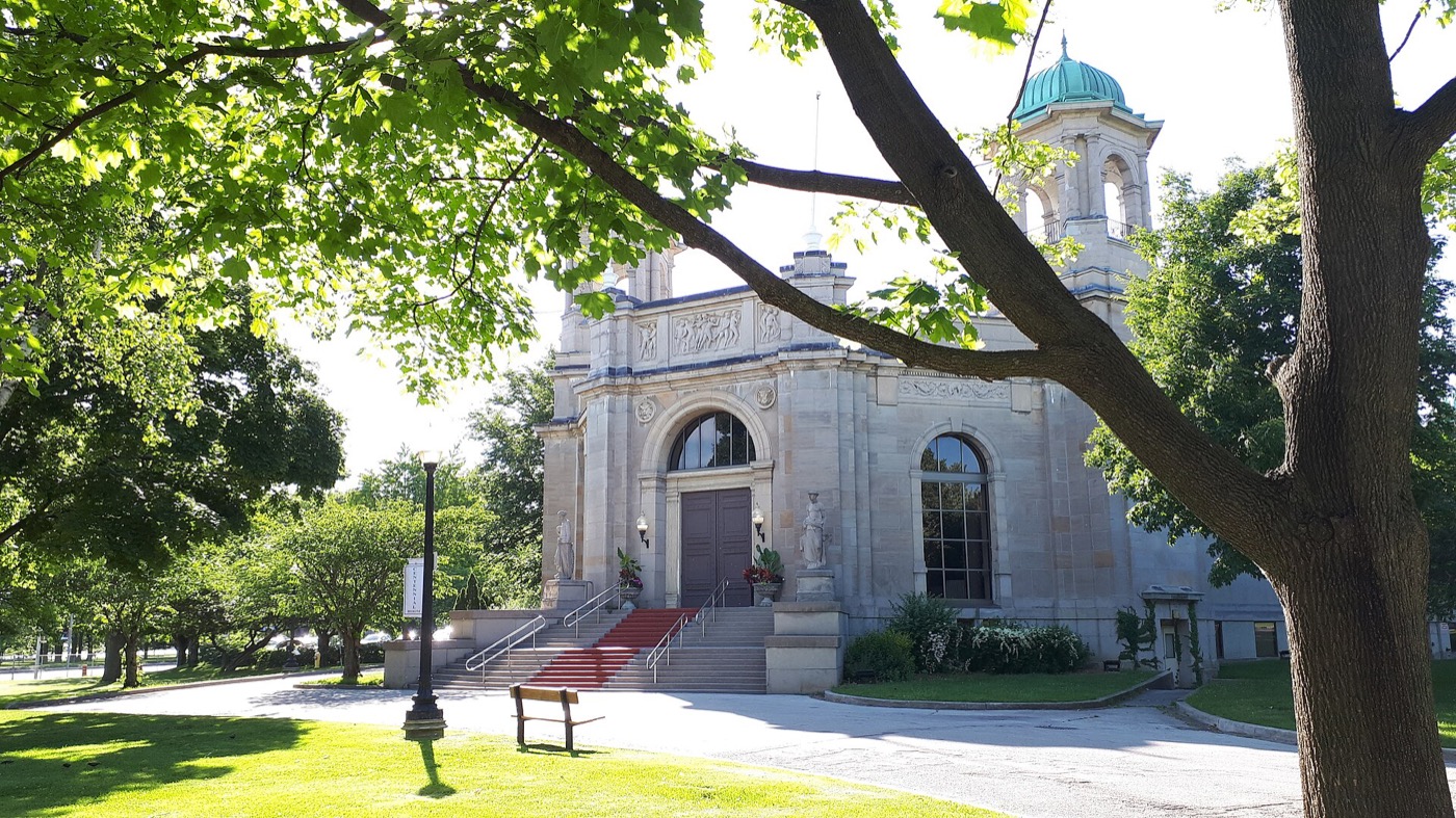 Liberty Grand at Exhibition Place, Toronto: the Beaux-Arts stone facade with a green dome and red-carpeted steps, seen through trees