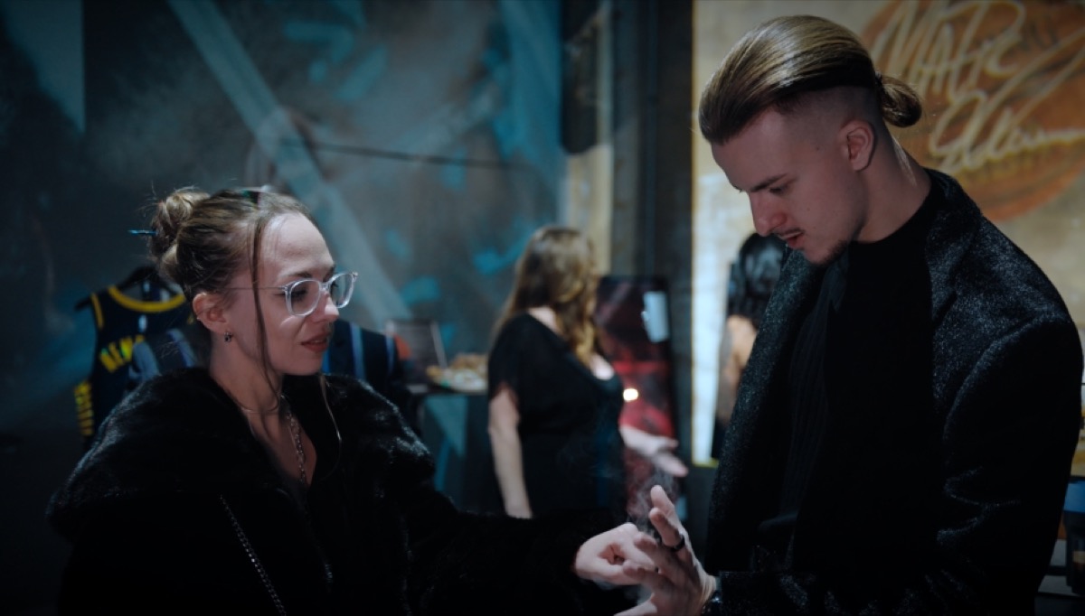 Roman Royss showing close-up magic to a guest in glasses at an evening event