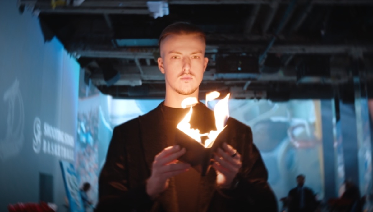 Roman Royss holding a flaming wallet at an evening event