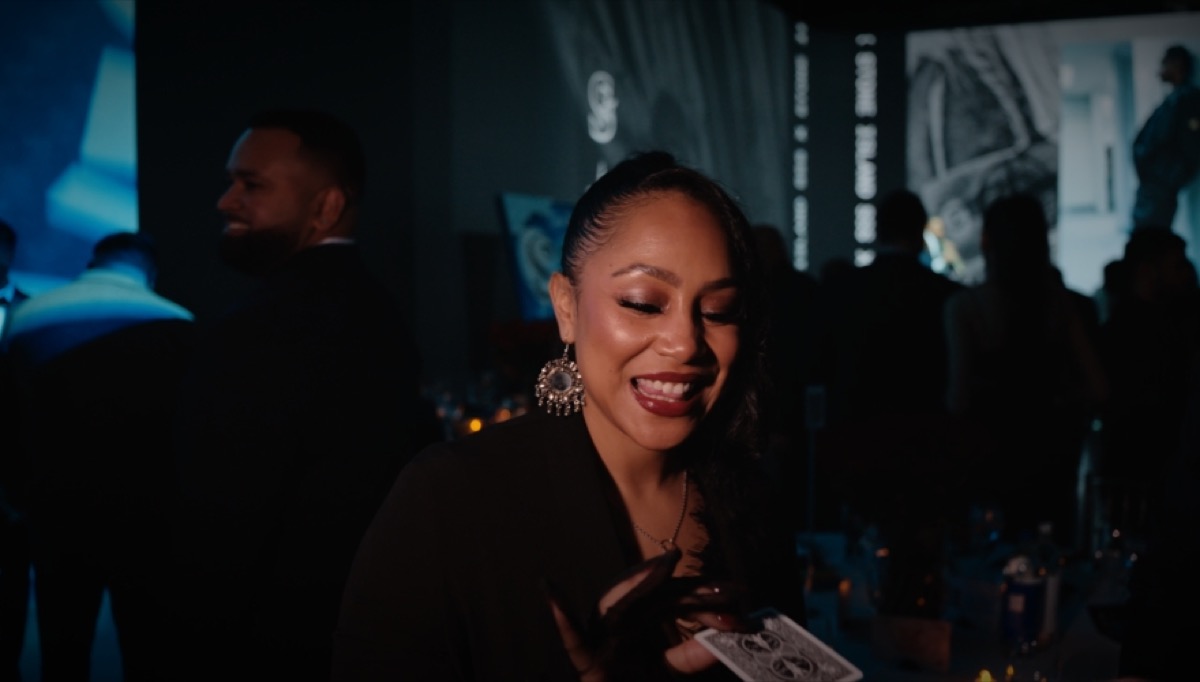 A smiling guest holding a playing card at an evening event
